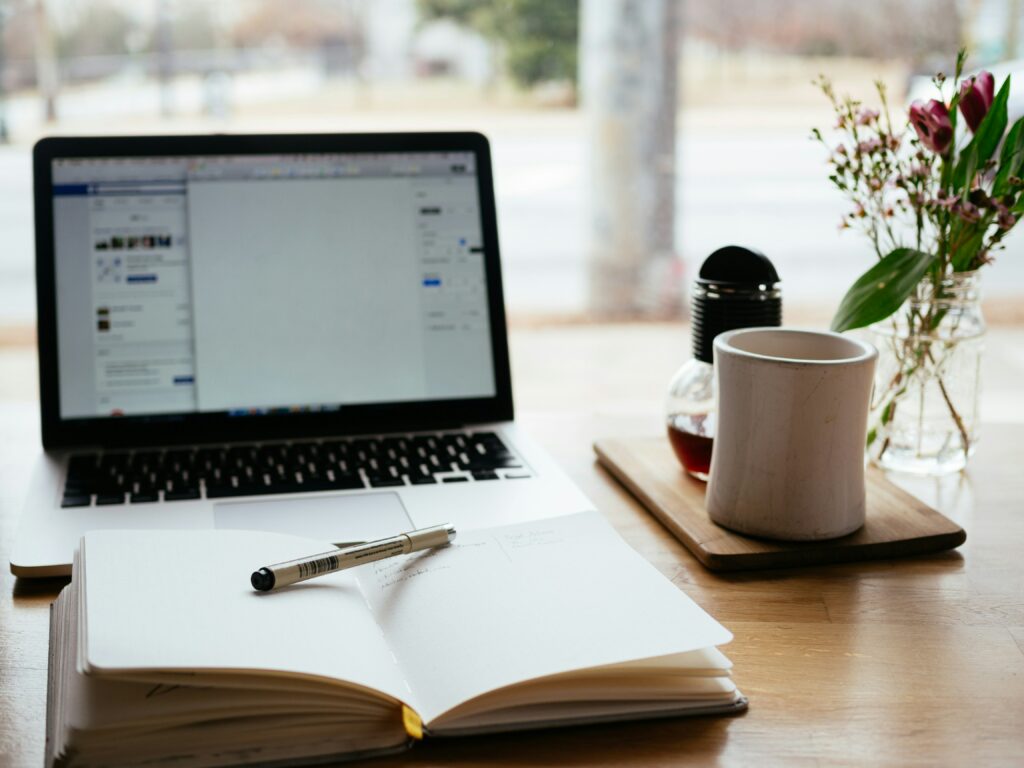 nick-morrison-FHnnjk1Yj7Y-unsplash Image décorative représentant un agenda ouvert devant ordinateur allumé sur une table. Un stylo est posé dessus, prêt à noter la date de notre premier entretien !